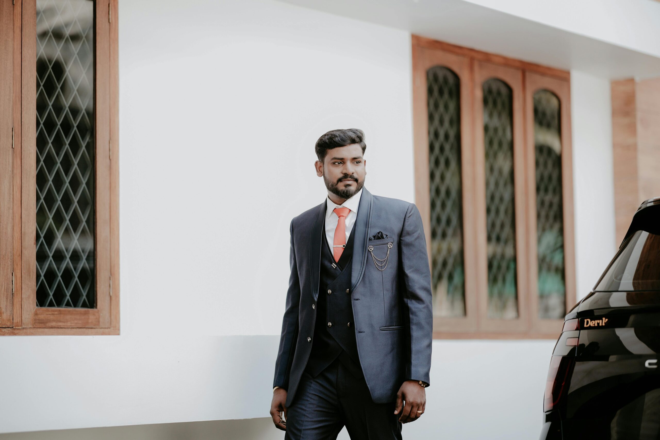Indian groom in a stylish blue suit, posing outdoors with a confident expression.